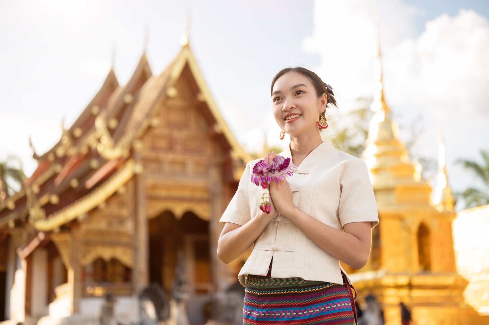 A beautiful Thai woman in a Thai-Lanna dress is putting her hands together in a prayer position.